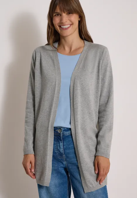 Offener Cardigan in langer Passform mineral grey melange Frau im grauen Cardigan, blauem Shirt und Jeans lächelt vor neutralem Hintergrund.