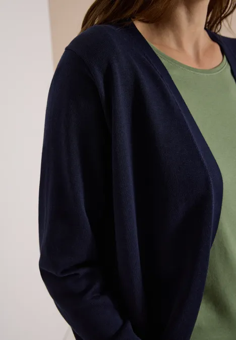 Vrouw in een donkerblauwe cardigan over een groen shirt