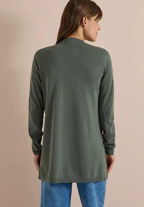 Frau von hinten trägt lange grüne Strickjacke und blaue Jeans.
