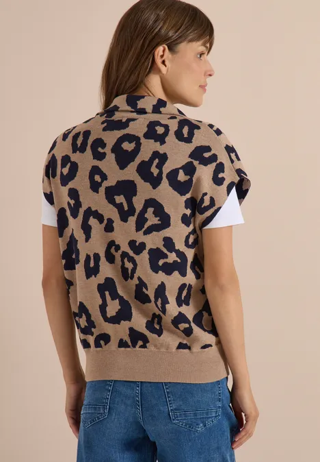 Beige Strickweste mit Leopardenmuster über weißem T-Shirt, kombiniert mit blauen Jeans.