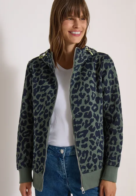 Sweatjacke mit Kapuze und Leo-Muster dried olive green Frau trägt grüne Bomberjacke mit schwarzem Leopardenmuster, kombiniert mit weißem Shirt und Jeans.