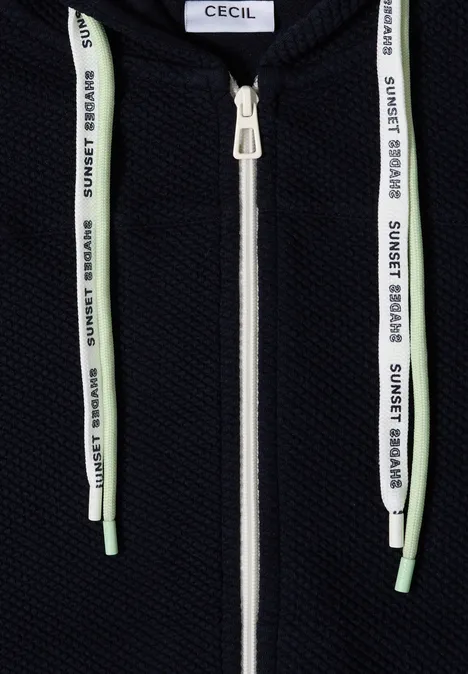 Zwarte hoodie met witte rits en witte koordjes bedrukt met groen "SUNSET BOARD"-logo.