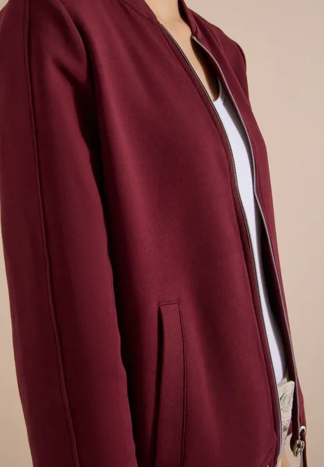 Sweat Blouson mit Tunnelzug red wine Nahaufnahme einer burgunderfarbenen Bomberjacke, leicht geöffnet, mit seitlicher Tasche und weißem Shirt darunter.