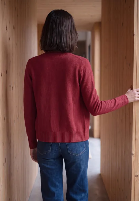 Langarm Cardigan mit Rundhals und Zipper rhubarb melange Eine Person steht mit dem Rücken zur Kamera in einem Holzflur, trägt roten Pullover und blaue Jeans.