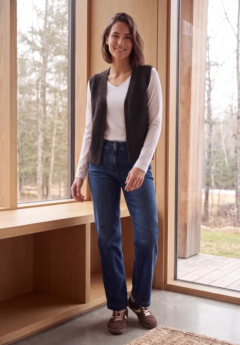 Open vest van veergaren in effen kleur berry red Eine Frau in Jeans, weißem Shirt und Weste steht lächelnd vor einem großen Fenster mit Blick auf Wälder.