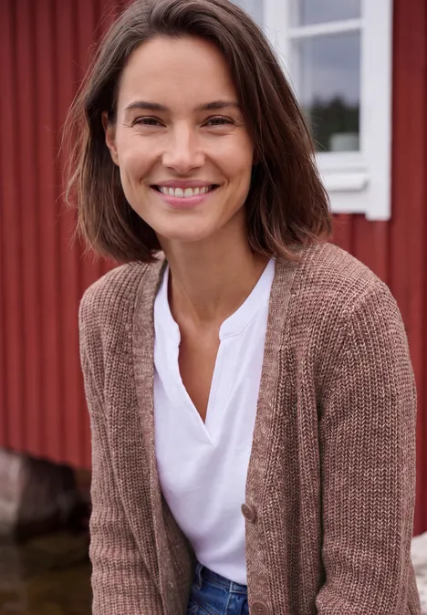 Chunky Cardigan mit V-Neck und Melange-Optik dark russet red melange Eine lächelnde Frau mit weißem Top und brauner Strickjacke steht vor einem roten Gebäude im Freien.