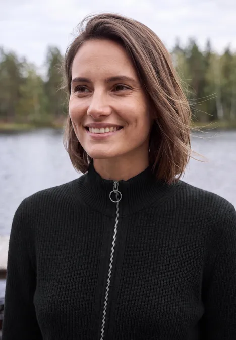Cardigan mit Stehkragen und Zipper Black Frau steht lachend am Ufer vor Wald und Wasser