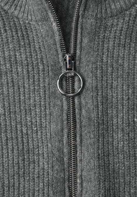 Cardigan zippé à col montant flint grey melange Nahaufnahme eines grauen Strickpullovers mit Reißverschluss und rundem Zipper-Anhänger.