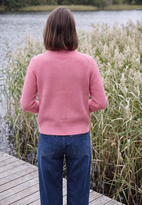 Cardigan mit Stehkragen und Zipper dark blossom melange Person steht am Wasser, Rücken zur Kamera, trägt rosa Pullover, blaue Jeans, im Hintergrund Schilf.