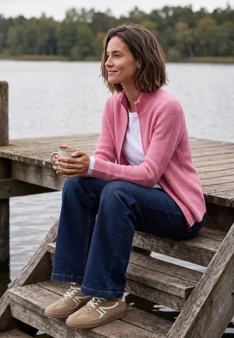 Cardigan mit Stehkragen und Zipper dark blossom melange Frau in rosa Strickjacke sitzt auf einer Holztreppe am See, hält eine Tasse und blickt entspannt in die Ferne.