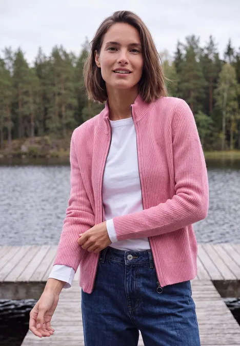 Cardigan mit Stehkragen und Zipper dark blossom melange Eine Frau mit rosa Strickjacke und Jeans steht auf einem Steg vor einem Waldsee und lächelt in die Kamera.