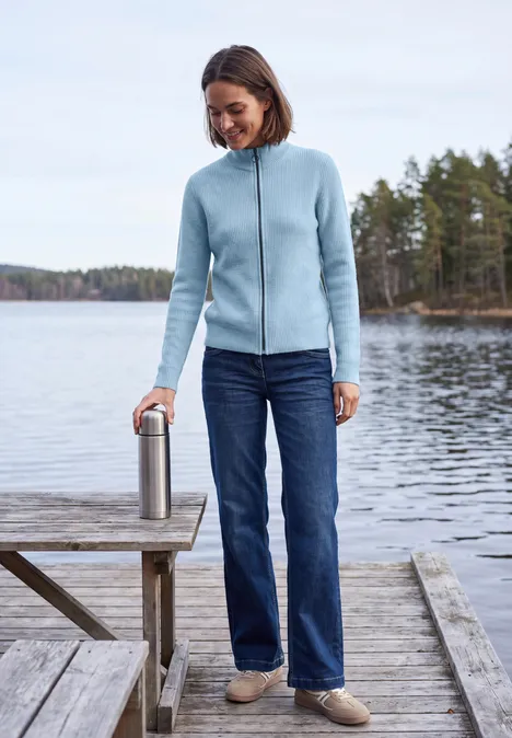 Cardigan mit Stehkragen und Zipper cosmopolitan blue Frau in blauer Fleecejacke, Jeans und Hausschuhen steht auf Steg am See und hält eine Thermoskanne.