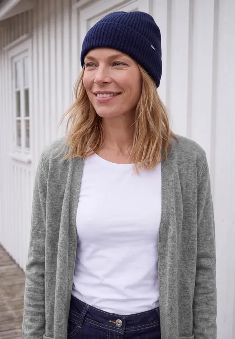 Langer Cardigan in offener Passform sporty grey melange Eine lächelnde Frau in Strickmütze, weißem Shirt und grauem Cardigan steht vor hellem Holzhaus.