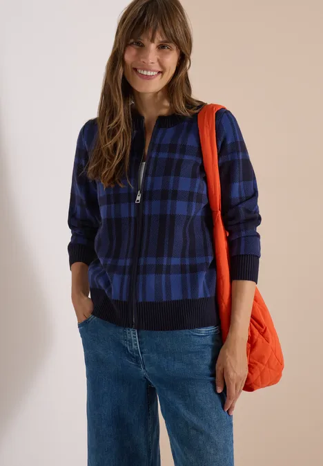 Langarm Cardigan mit Rundhals und Zipper urban dark blue Frau lächelt, trägt eine blau-karierten Zip-Jacke, Jeans und eine orange Tasche.