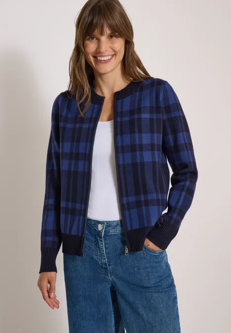 Langarm Cardigan mit Rundhals und Zipper urban dark blue Frau in blau-schwarz kariertem Cardigan, weißem Shirt und Jeans, lächelt vor neutralem Hintergrund.