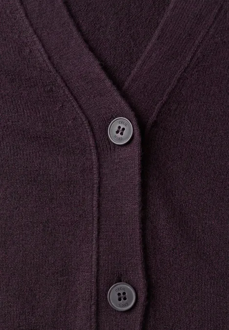 Nahaufnahme eines dunkelvioletten Strickcardigans mit V-Ausschnitt und zwei Knöpfen.