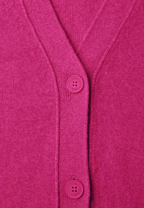 Close-up van een roze vest met V-hals en twee knopen, gemaakt van zacht gebreid materiaal.