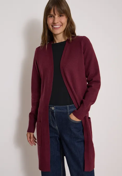 Langer Cardigan in offener Passform red wine Frau in dunkelrotem Cardigan, schwarzem Shirt und Jeans, lächelnd vor weißem Hintergrund