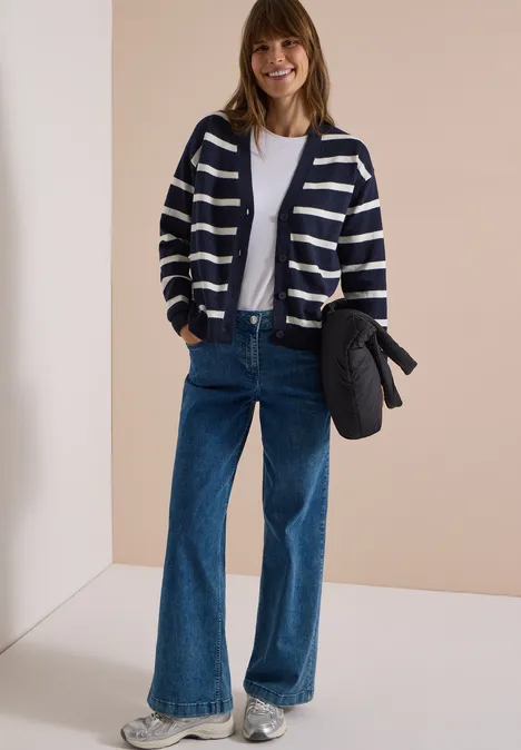 Vest met V-hals en strepen urban dark blue melange Frau in gestreifter Strickjacke, weißem T-Shirt und weitem Jeans, hält eine Tasche, lächelnd.