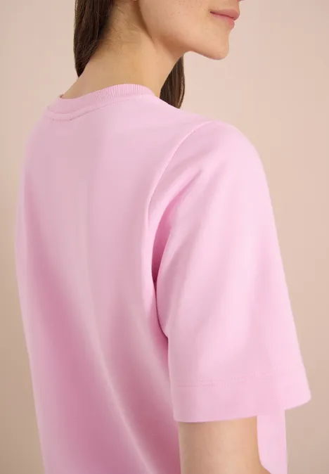 Sweater met korte mouwen en ronde hals light blush rose Achteraanzicht van een persoon in een lichtroze T-shirt tegen een neutrale achtergrond.