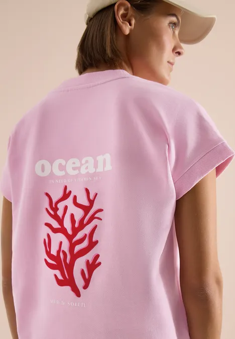 Sweater met korte mouwen en rugprint light blush rose Iemand draagt een roze T-shirt met de tekst 'ocean' en een rode koraal op de rug.