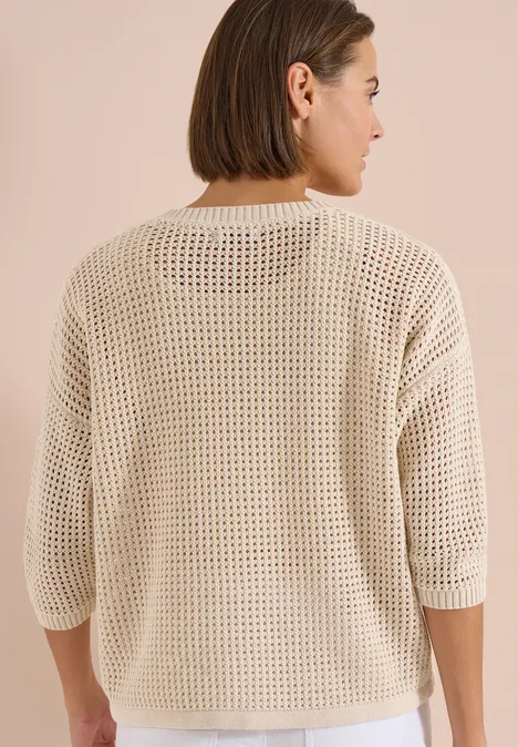 Frau von hinten in lockerem, beigem Netzstrick-Pullover mit 3/4-Ärmeln.