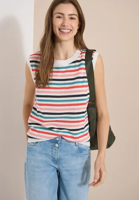 Personne porte un top sans manches à rayures, un jean bleu et un sac à dos sur fond clair.