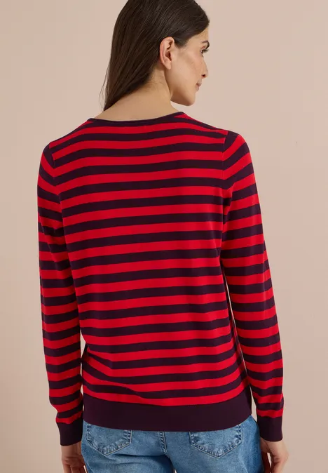 Trui met ronde hals en strepen eggplant red Vrouw van achteren in een rood-blauw gestreepte trui met lange mouwen en een spijkerbroek, neutrale achtergrond.