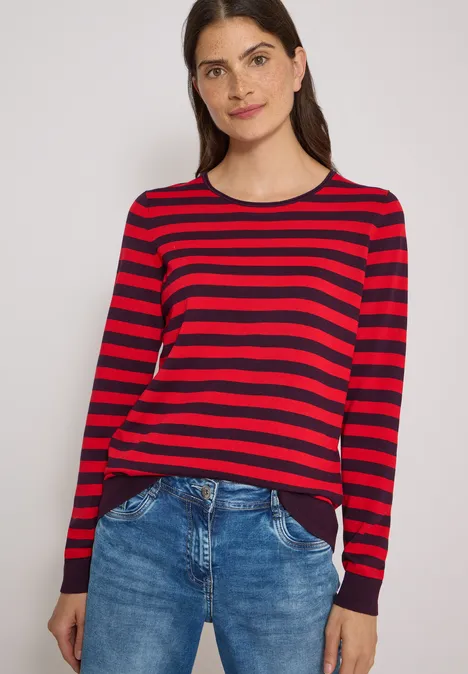 Trui met ronde hals en strepen eggplant red Vrouw draagt rood-zwarte gestreepte trui met lange mouwen en blauwe spijkerbroek.