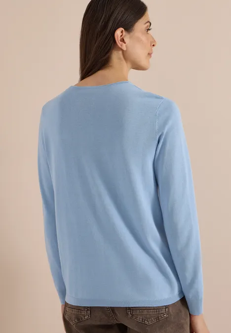 Basic Pullover mit Rundhals easy blue Frau von hinten in hellblauem Pullover und dunkler Hose vor neutralem Hintergrund.