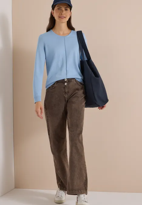 Basic Pullover mit Rundhals easy blue Frau mit hellblauem Cardigan, brauner Cordhose, weißen Sneakern, dunkelblauer Cap und passender Umhängetasche.