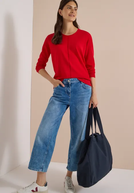 Basic Pullover mit Rundhals flame red Frau in rotem Pullover, weiten Jeans und weißen Sneakern, die eine große blaue Tasche trägt.