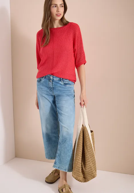 Dolman Pullover mit U-Boot-Ausschnitt coral Frau in rotem Dreiviertelarmshirt, weiten Capri-Jeans und Lederloafers trägt eine Strohtasche.