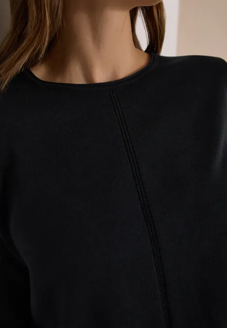 Basic Pullover mit Rundhals in Unifarbe Black Nahaufnahme einer Frau mit schwarzem Oberteil, das eine vertikale Naht in der Mitte aufweist.
