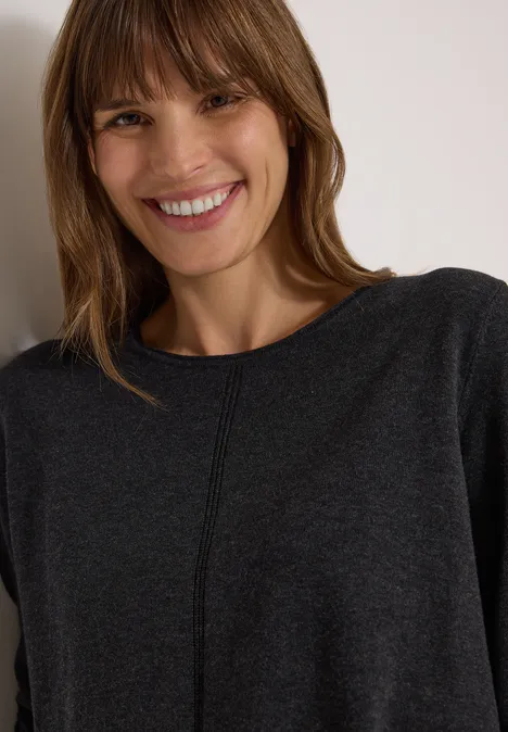 Basic Pullover mit Rundhals in Unifarbe charcoal grey melange Frau mit kastanienbraunen Haaren und Fransenschnitt in grauem Pullover, die freundlich in die Kamera lächelt.