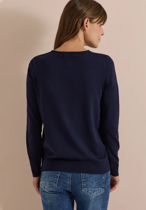 Basic Pullover mit Rundhals in Unifarbe urban dark blue Eine Frau von hinten in dunkelblauem Pullover und Jeans vor beigem Hintergrund.