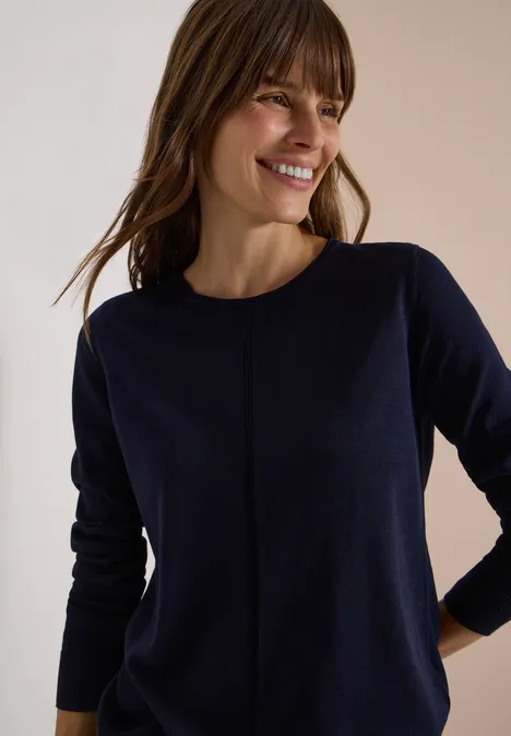 Basic Pullover mit Rundhals in Unifarbe urban dark blue Eine lächelnde Frau trägt einen dunkelblauen Feinstrickpullover, steht entspannt mit Händen an der Hüfte.