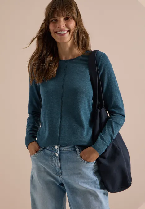 Basic Pullover mit Rundhals in Unifarbe dull teal blue melange Eine lächelnde Frau in petrolfarbenem Pullover, Jeans und blauer Umhängetasche vor neutralem Hintergrund.