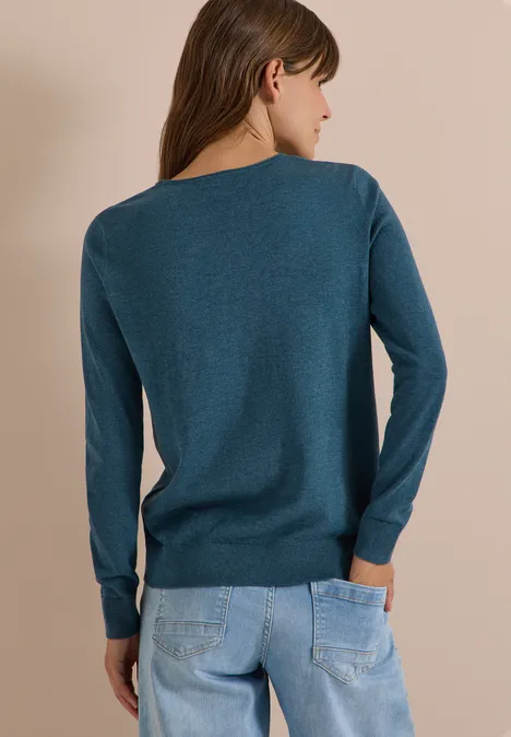 Basic Pullover mit Rundhals in Unifarbe dull teal blue melange Frau von hinten in petrolfarbenem Pullover und hellblauen Jeans vor neutralem Hintergrund.