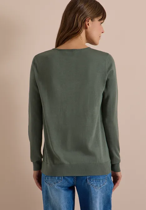 Basic Pullover mit Rundhals in Unifarbe dried olive green Eine Frau von hinten, trägt einen schlichten grünen Pullover und blaue Jeans vor neutralem Hintergrund.