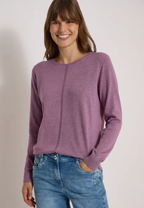 Basic Pullover mit Rundhals in Unifarbe lavender purple melange Eine lächelnde Frau in lila Langarmshirt und blauen Jeans vor neutralem Hintergrund.
