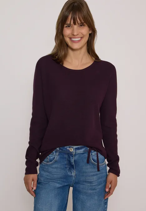 Pullover mit Rundhals und Struktur eggplant red Frau trägt lockeren lila Pullover und blaue Jeans, lächelt vor hellem Hintergrund