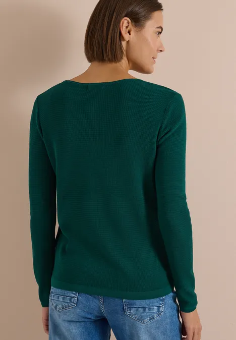 Pullover mit Rundhals und Struktur dark fir green Frau von hinten im grünen Pullover vor beigem Hintergrund.