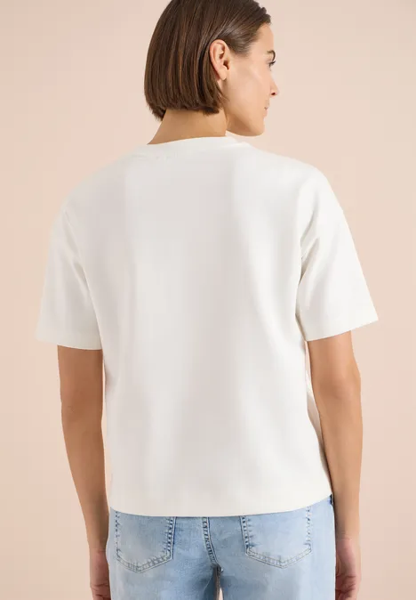 Persoon van achteren in een effen wit T-shirt en een blauwe spijkerbroek.