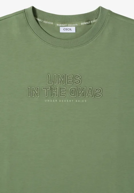 Olivgroen T-shirt met korte mouwen en witte print 'LINES IN THE SAND2' en kleine tekst 'UNDER DESERT SKIES'.