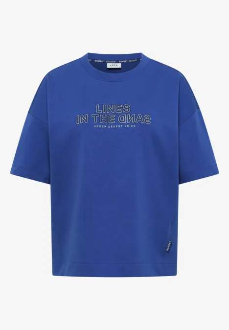 Rechthoekig gesneden koningsblauw T-shirt met zilverkleurige tekst 'LINES IN THE CHAOS'.