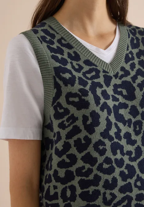 Damen-Look: grüner Leo-Strickpullunder über weißem T-Shirt, V-Ausschnitt, lässiger Stil.
