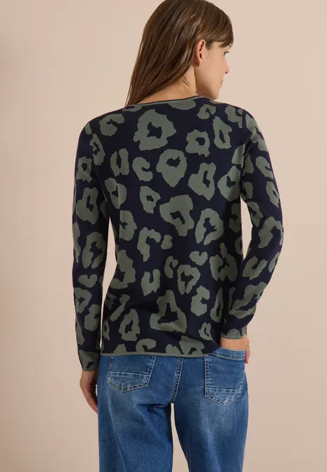 Frau von hinten in schwarzem, grünen Leopardenmuster-Pullover und blauer Jeans