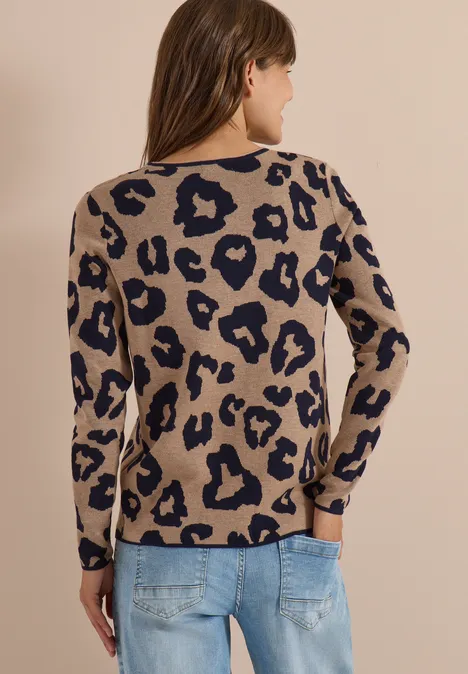 Frau von hinten in beigem Pullover mit Leopardenmuster und blauen Jeans