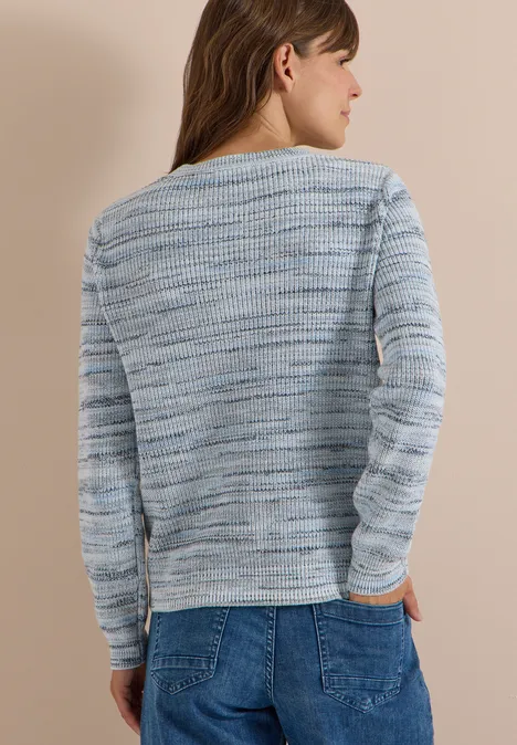 Rückansicht einer Frau in locker gestricktem, hellblau-grau meliertem Pullover und Jeans.